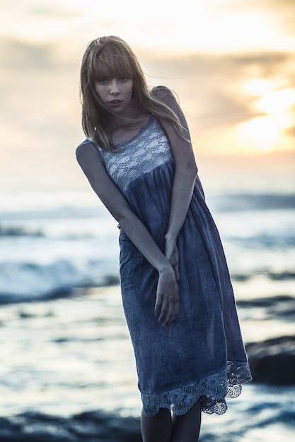 Hermosa joven modelo de pie en las rocas junto al mar