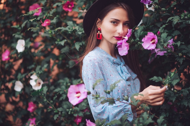 Hermosa joven modelo posando con flores florecientes