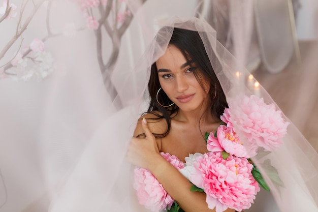 Hermosa joven modelo sosteniendo flores de colores y mirando a la cámara Foto de alta calidad