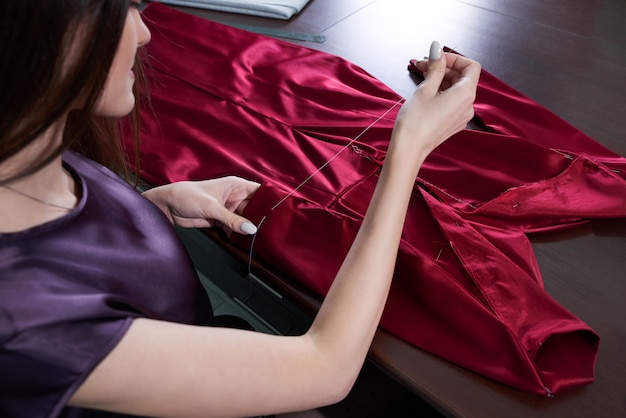 Hermosa joven modista en el taller de costura vestido rojo