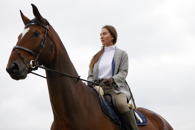 Hermosa joven montando a caballo al aire libre Concepto de cuidado de animales Descanso rural y ocio Idea de turismo verde Joven europea con casco y uniforme