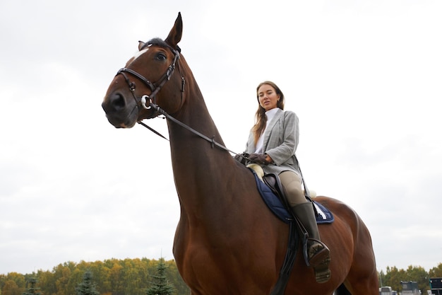 Hermosa joven montando un caballo en el campo De lado a la cámara Movimiento de alegría de libertad