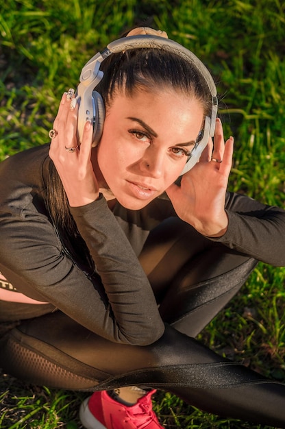 Hermosa joven morena con auriculares al aire libre./Linda chica deportiva con auriculares escuchando música.