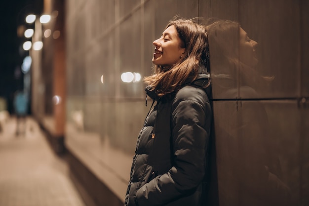 Hermosa joven morena en una ciudad de noche en chaqueta