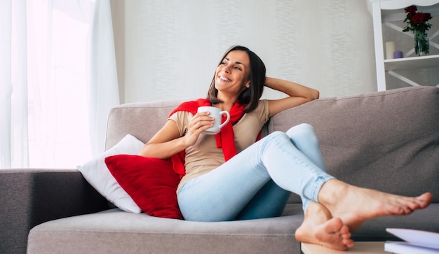 Foto hermosa joven morena feliz se está relajando en el sofá en casa y soñando