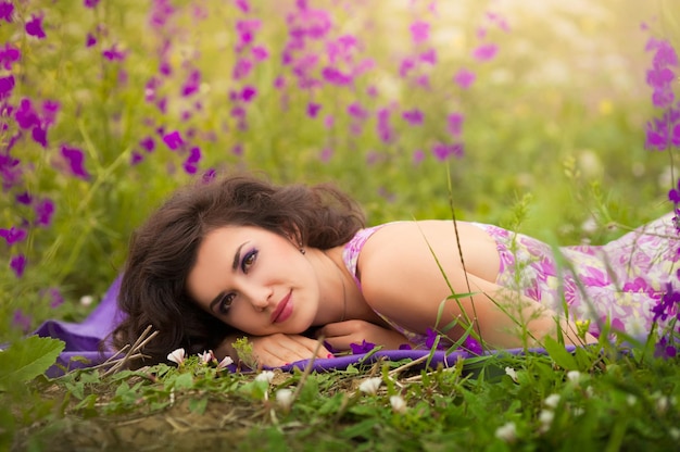 Hermosa joven morena con flores de color púrpura al aire libre