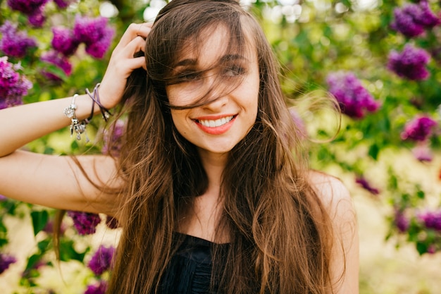 Hermosa joven morena posando en el parque en flor.