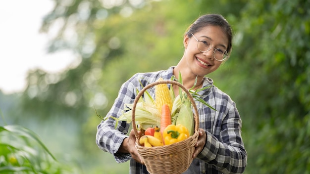 Hermosa joven morena Retrato Famer Mujer mano sosteniendo Verduras en la cesta de bambú en verde