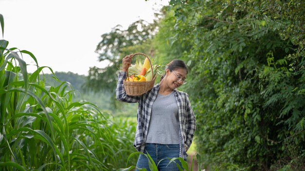 Hermosa joven morena Retrato Famer Mujer mano sosteniendo Verduras en la cesta de bambú en verde