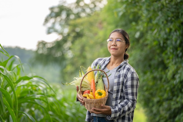 Hermosa joven morena Retrato Famer Mujer mano sosteniendo Verduras en la cesta de bambú en verde