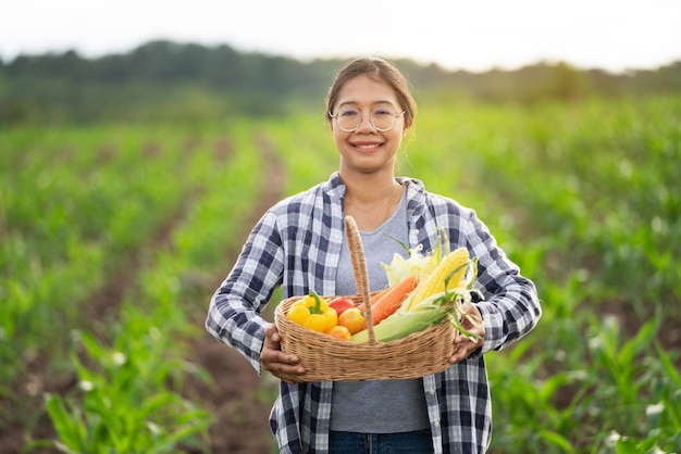 Hermosa joven morena Retrato Famer Mujer mano sujetando Verduras en la cesta de bambú