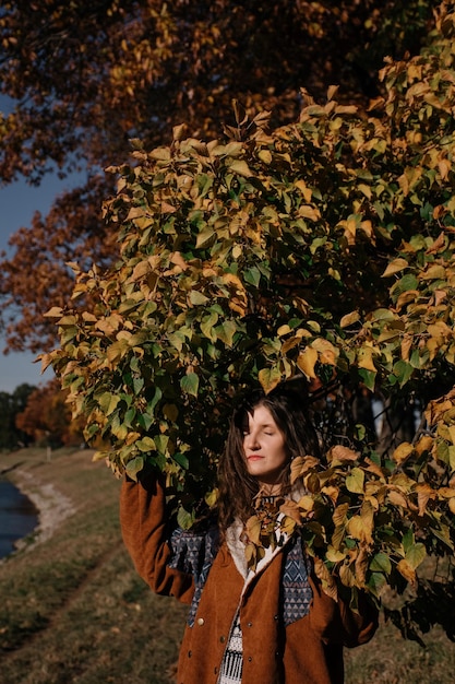 Hermosa joven morena soñadora en el bosque de otoño.