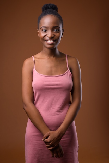 Hermosa joven mujer africana Zulú sonriendo contra el fondo marrón