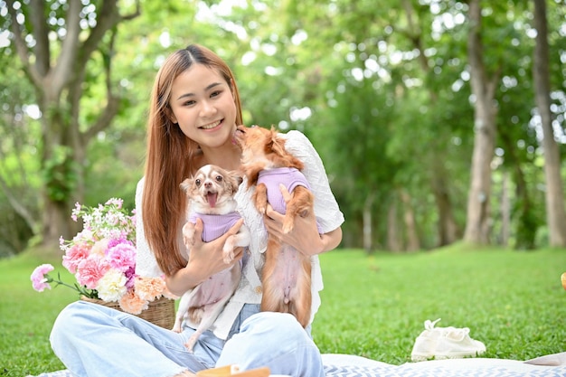 Hermosa joven mujer asiática picnic en el jardín con sus adorables perros