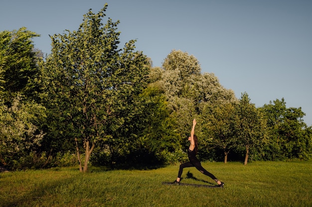 Hermosa joven mujer caucásica haciendo práctica de yoga en el parque ejercicio femenino joven