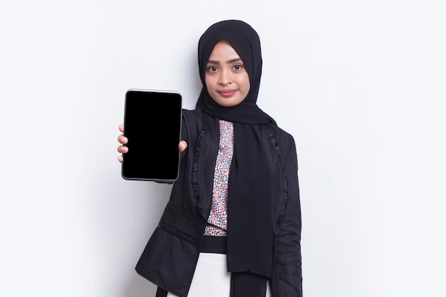Hermosa joven mujer musulmana asiática demostrando teléfono celular móvil aislado sobre fondo blanco.