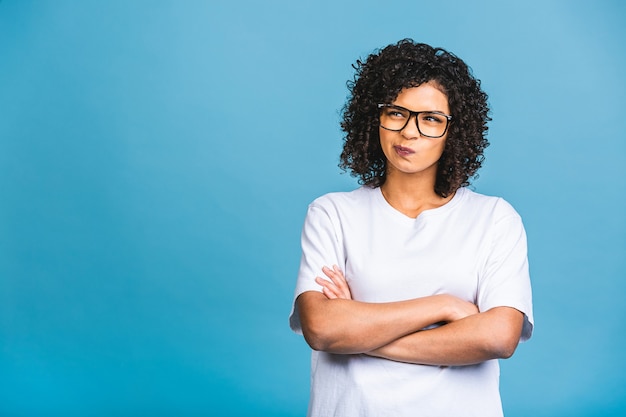 Hermosa joven mujer de negocios afroamericana sobre fondo azul aislado con la mano en los labios pensando en la pregunta, expresión pensativa. Sonriendo con rostro pensativo. Concepto de duda.