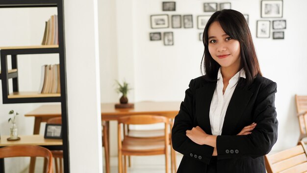 Hermosa joven mujer de negocios asiática en traje de pie en el café