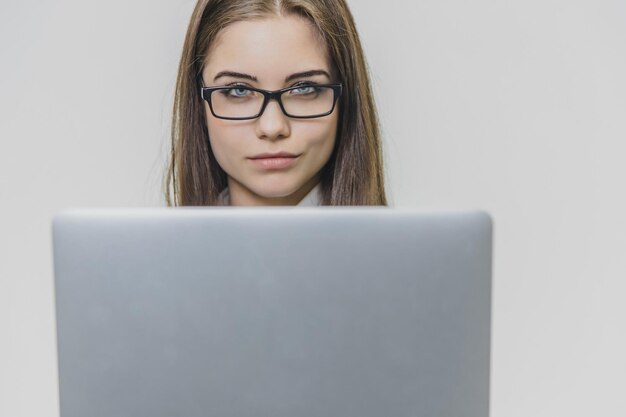Una hermosa joven mujer de negocios lleva gafas y usa una pantalla táctil de computadora moderna una empleadora confiada está trabajando y está concentrada una chica está mirando a la cámara