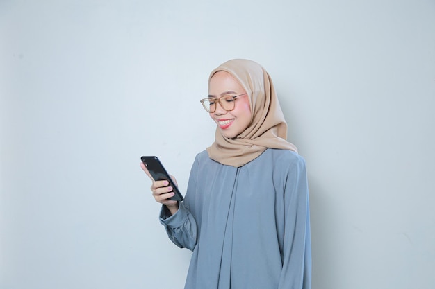 Hermosa joven mujer de negocios musulmana asiática con gafas usando teléfono móvil