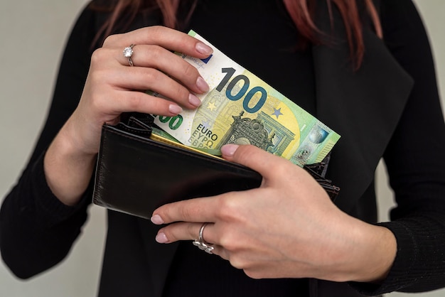 hermosa joven mujer de negocios con ropa elegante sosteniendo un gran bolso con billetes en euros. Concepto de billetera completa