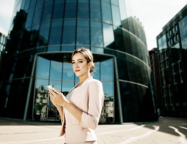 Hermosa joven mujer de negocios usa un teléfono móvil frente a un moderno centro de negocios