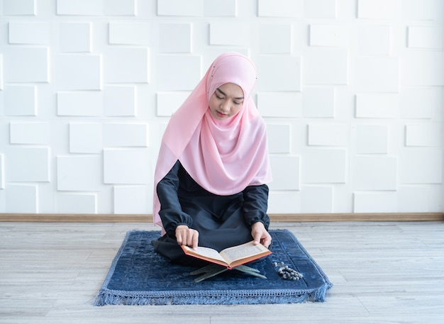 Hermosa joven musulmana asiática mujer leyendo el Corán