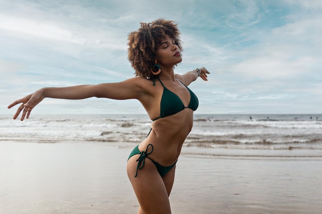 Hermosa joven negra africana en bikini feliz en la playa
