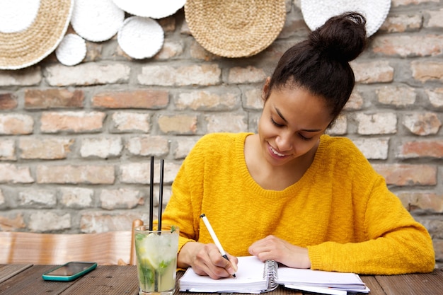 Hermosa joven negra escribiendo notas en el café