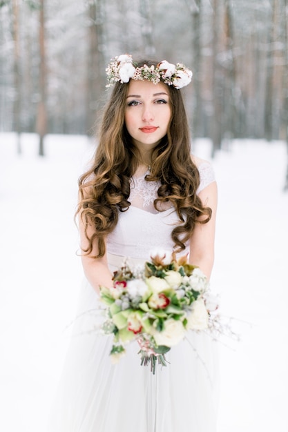 Hermosa joven novia en el bosque nevado de invierno