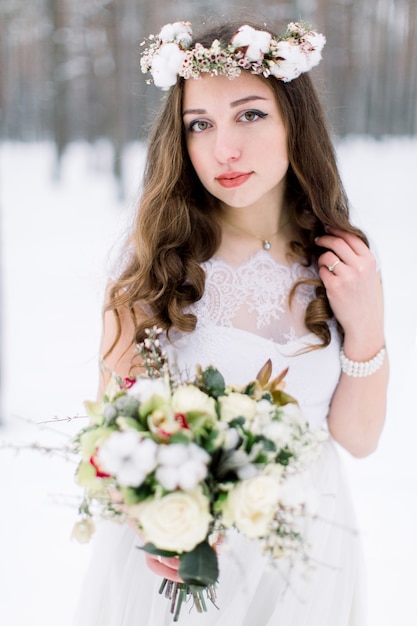 Hermosa joven novia en el bosque nevado de invierno