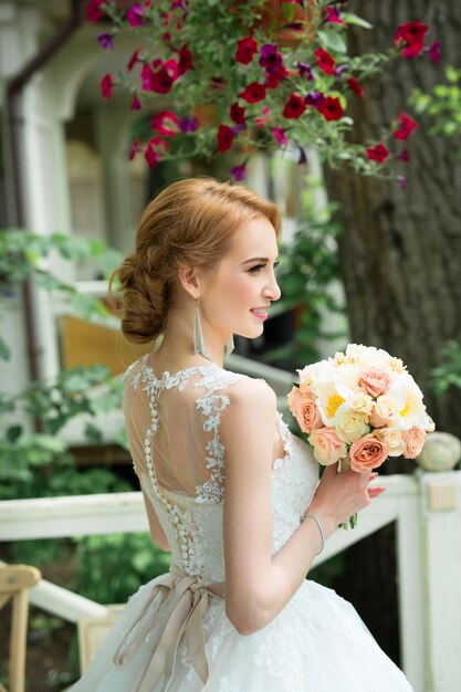 hermosa joven novia en un delicado vestido de novia con un ramo