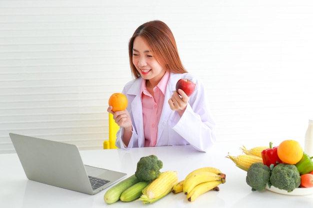 Hermosa joven nutricionista que se ocupa de la salud de los pacientes Brinda consejos sobre alimentos a los pacientes a través de computadoras portátiles concepto de opciones de alimentos saludables por un médico que consulta