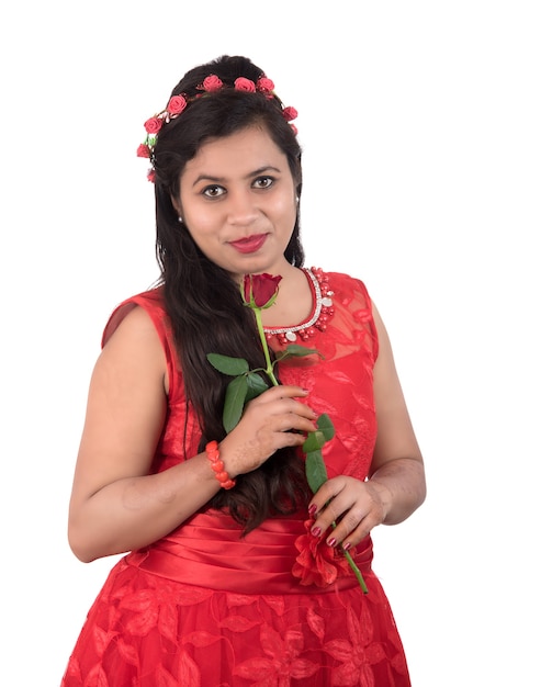 Hermosa joven o mujer sosteniendo y posando con flor rosa roja sobre blanco