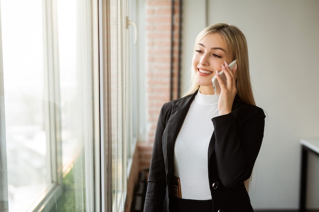 hermosa joven en la oficina con un teléfono móvil