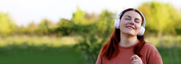 Hermosa joven con los ojos cerrados escuchando música a través de auriculares y bailando