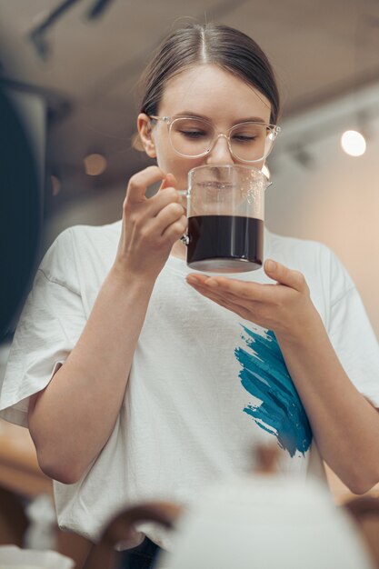 Hermosa joven oliendo café en la cafetería