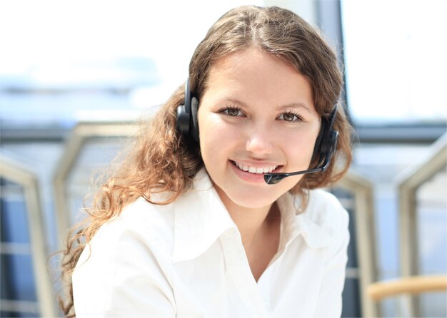 Hermosa joven operador de centro de llamadas con auriculares en la oficina