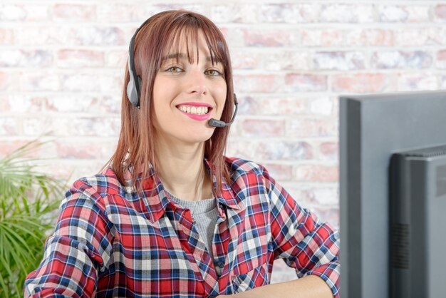 Hermosa joven operador de telefonía de apoyo con auriculares