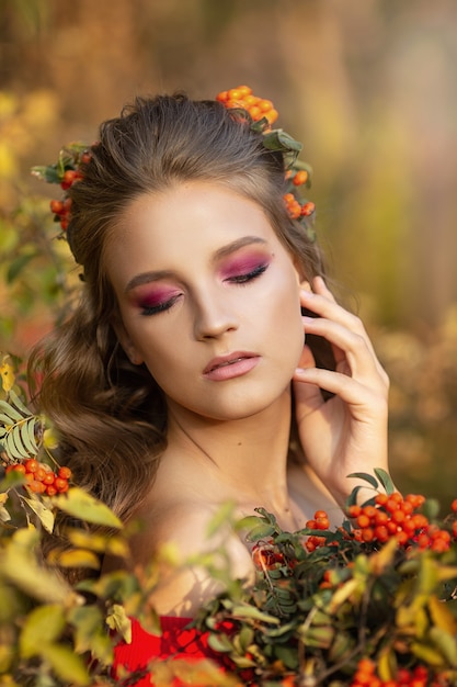 Hermosa joven en otoño con bayas de fresno de montaña