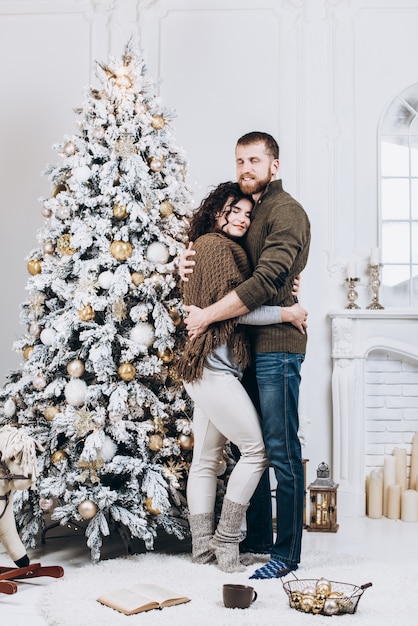 Hermosa joven pareja abrazándose cerca de árbol de Navidad. Navidad y año nuevo concepto