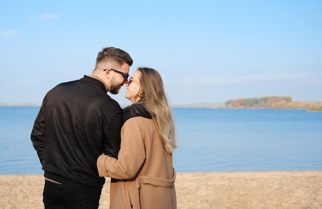 Hermosa joven pareja abrazándose en la playa durante la estación fría en un clima soleado