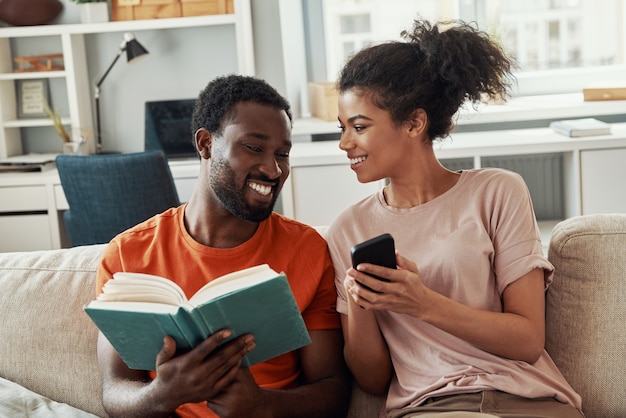 Hermosa joven pareja africana disfrutando de sus pasatiempos mientras pasa tiempo en casa