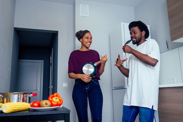 Hermosa joven pareja afroamericana sonríe mientras baila en la cocina