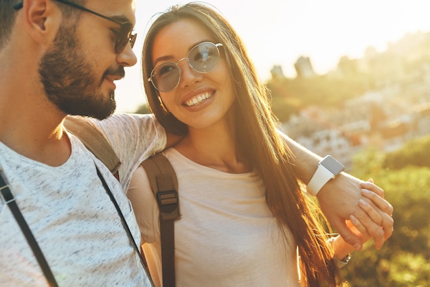 Hermosa joven pareja amorosa abrazándose y sonriendo mientras pasa tiempo al aire libre