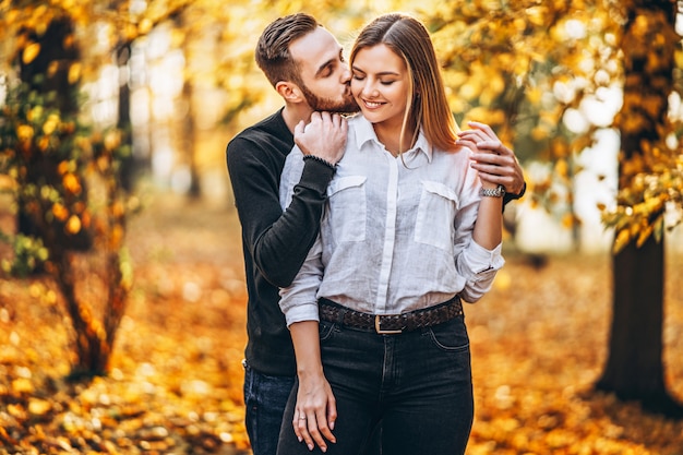 Hermosa joven pareja caminando en el parque de otoño en un día soleado