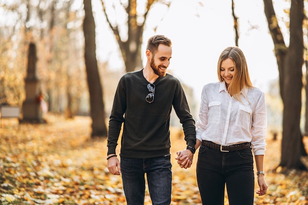 Hermosa joven pareja caminando en el parque de otoño en un día soleado