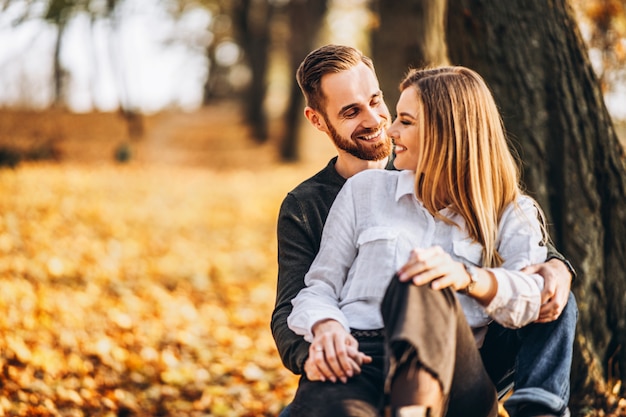 Hermosa joven pareja caminando en el parque de otoño en un día soleado