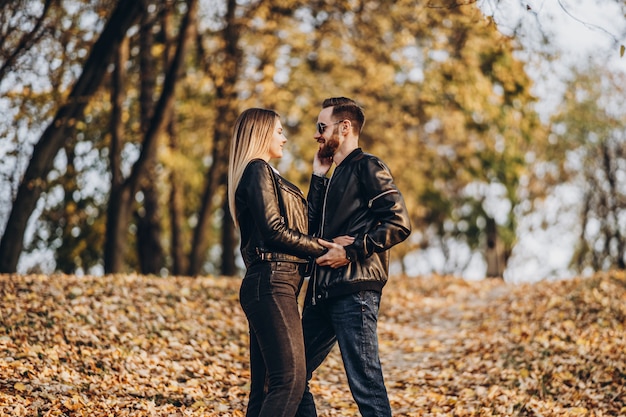 Hermosa joven pareja caminando en el parque de otoño en un día soleado