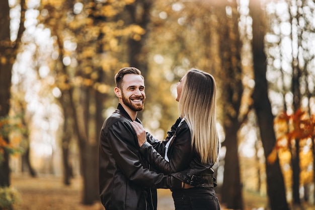 Hermosa joven pareja caminando en el parque de otoño en un día soleado